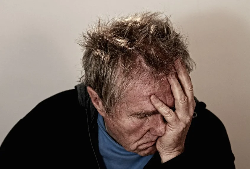 man in depression holding his face