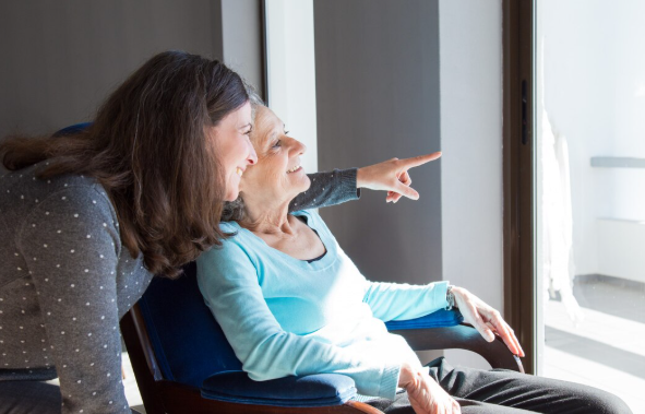 Caregiver assisting an elderly Alzheimer’s patient at home with emotional support and daily care activities.