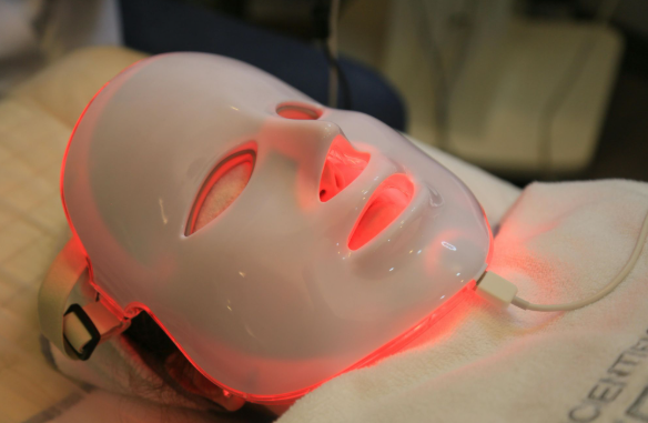 Modern home wellness technology devices including red light therapy panel, wearable tracker, and PEMF therapy on patient